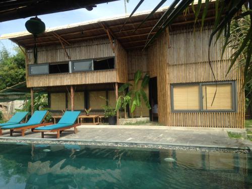 a house with a swimming pool and blue chairs at Home Farm Villa Hoi An in Hoi An