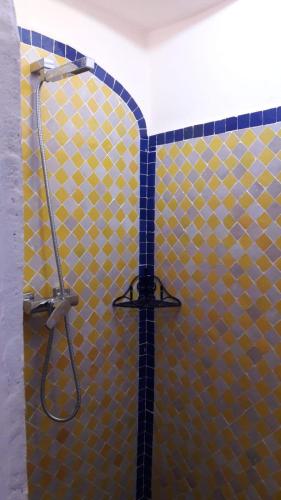 a shower with a yellow and blue tiled wall at Maison Mirage B&B in Hassilabied