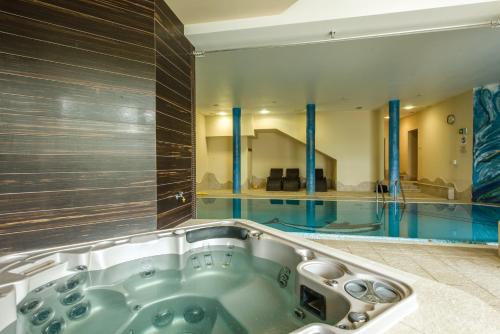 a bath tub in a bathroom with a swimming pool at Hotel Dziki Potok Karpacz Konferencje & SPA in Karpacz