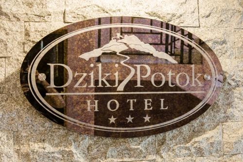 a sign for a hotel on a stone wall at Hotel Dziki Potok Karpacz Konferencje & SPA in Karpacz