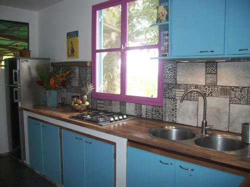 a kitchen with blue cabinets and a sink and a window at mango tree lodge in Bouillante