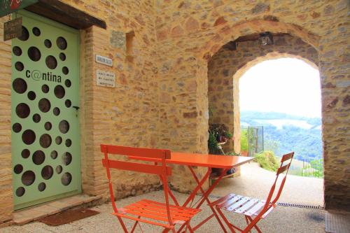 uma mesa vermelha e duas cadeiras ao lado de uma parede de pedra em Pekko em Spello