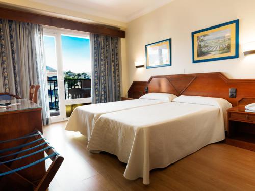 - une chambre avec un grand lit et une grande fenêtre dans l'établissement Hotel Monarque Fuengirola Park, à Fuengirola