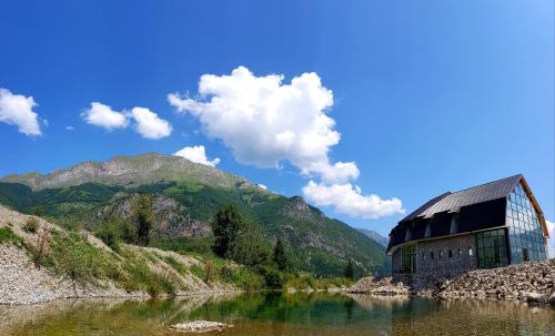 ein Gebäude an der Seite eines Flusses neben einem Berg in der Unterkunft Hotel & Restaurant Ada in Gusinje