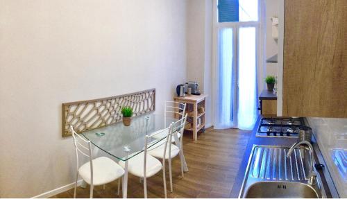 a kitchen with a glass table and white chairs at Bixio Suites in La Spezia