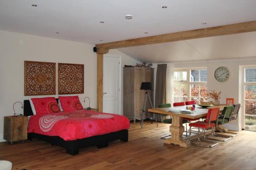 Hazerswoude-DorpにあるB&B Het Koetshuisのベッドルーム1室(赤いベッド1台、テーブル、椅子付)