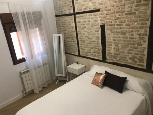 a bedroom with a white bed with a brick wall at Catedral toledo in Toledo