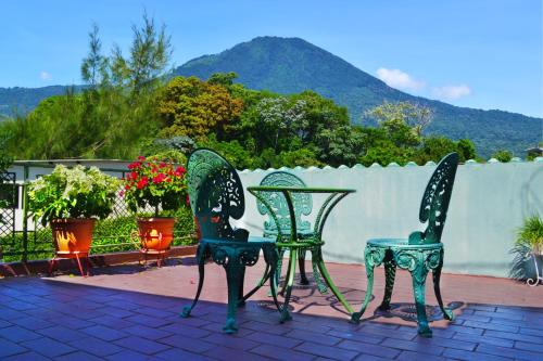 two green chairs and a table on a patio at Hotel Oasis in San Salvador