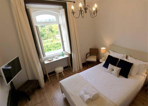 um quarto com uma grande cama branca e uma janela em Oryza Guest House& Suites em Coimbra