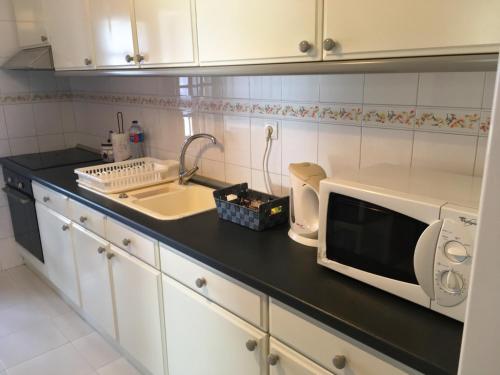 a kitchen counter with a microwave and a sink at Mira Maia Apartment in Maia