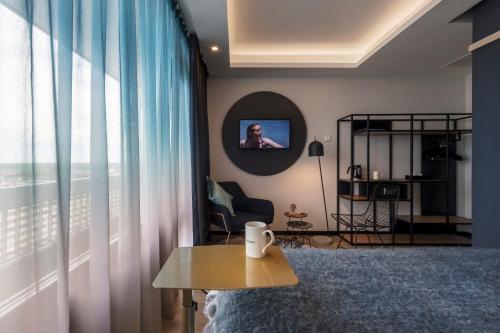 a living room with a table and a tv at Palace Hotel Zandvoort in Zandvoort
