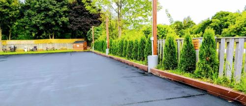 an empty parking lot with a fence and trees at Kings Inn Midland in Midland
