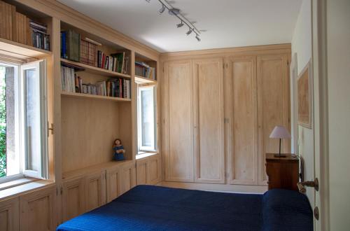 ein Schlafzimmer mit einem blauen Bett und Bücherregalen in der Unterkunft Charming rustic house in Gardone Riviera