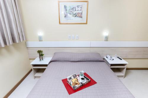 a room with a bed with a tray of food on it at Hotel Express Savoy - Centro Histórico in Porto Alegre