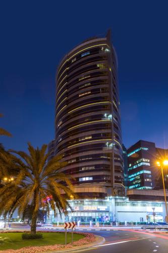 a tall building with a palm tree in front of it at Pearl Executive Hotel Apartments in Dubai