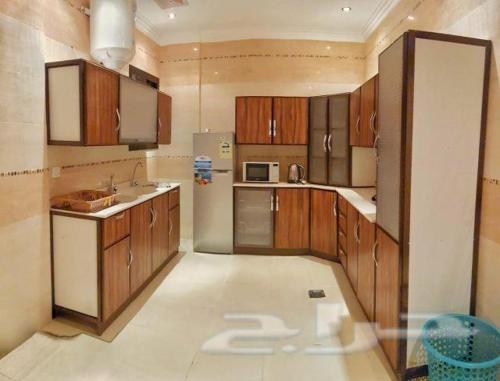 a large kitchen with wooden cabinets and a white appliance at Nadra Furnished Apartments in Taif