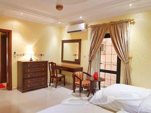 a bedroom with a desk and a bed and a table at Nadra Furnished Apartments in Taif