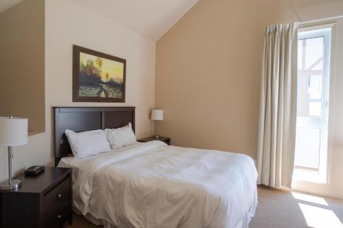 a bedroom with a white bed and a window at Condos Château-Bromont in Bromont