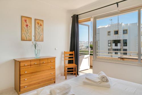 een slaapkamer met een bed, een dressoir en een raam bij Vilamoura WOWlidays in Vilamoura