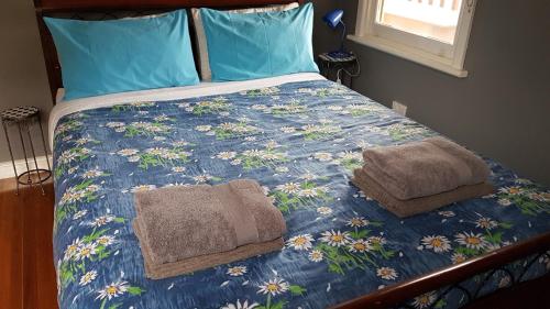a bed with a blue comforter with towels on it at Cottage on Main in Buchan