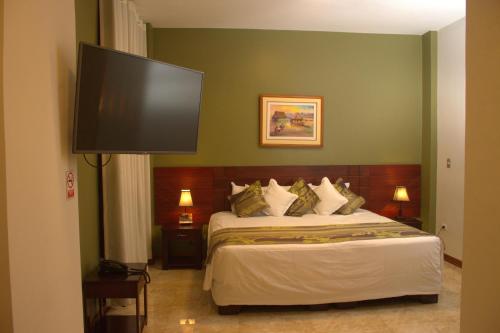 a bedroom with a bed with a flat screen tv on the wall at Hotel Europa in Iquitos