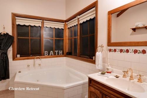 
a bathroom with a tub, sink, mirror, and bathtub at Glenview Retreat Luxury Accommodation in Emerald
