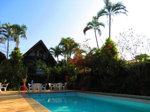a house with a swimming pool and palm trees at Casa Do Porto Pousada e Restaurante in Itaguaí