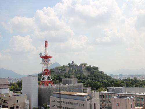 a red and white tower on top of a city at APA Hotel Marugame Ekimae Odori in Marugame