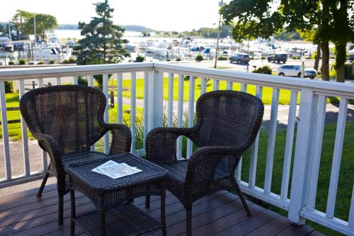 two chairs on a porch with a view of a harbor at Three Village Inn in Stony Brook