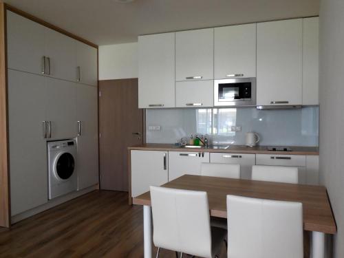 a kitchen with white cabinets and a table and chairs at Apartment Potter in Brno