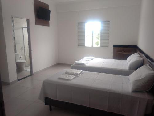 a bedroom with two beds and a bathroom at Hotel farol de Minas in Alpinópolis
