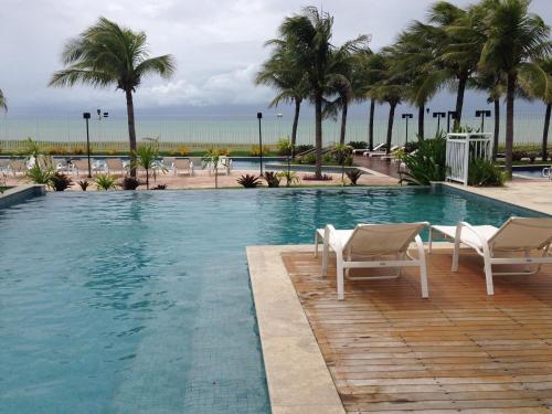 a swimming pool with two chairs and palm trees at In Mare Bali Residencial Resort in Pium de Cima