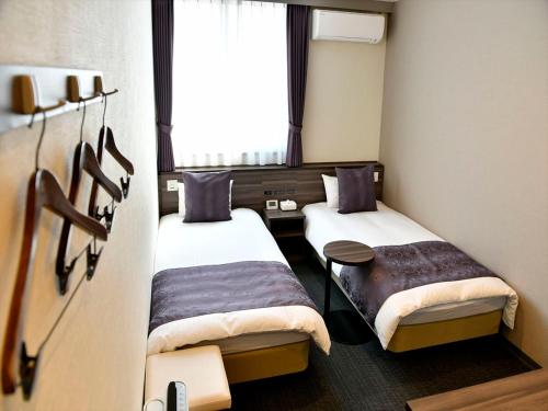 Habitación pequeña con 2 camas y ventana en New Commander Hotel Osaka Neyagawa en Neyagawa