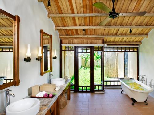 uma casa de banho com 2 lavatórios, uma banheira e uma ventoinha de tecto em Emeralda Resort Ninh Binh em Ninh Binh
