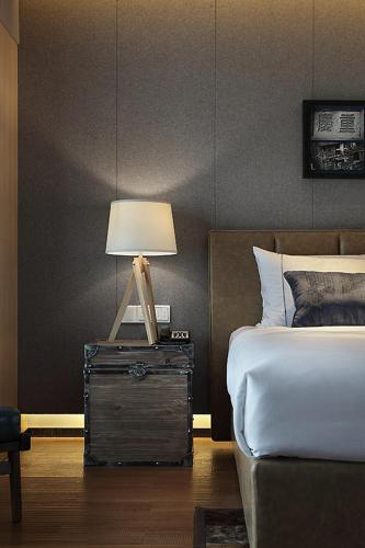 a bedroom with a bed and a lamp on a night stand at Bloom Boutique Hotel in Chongqing