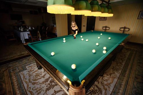 a woman playing a game of pool on a pool table at Best Western Plus Astana Hotel in Astana