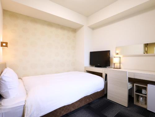 a hotel room with a bed and a flat screen tv at Hotel Wing International Himeji in Himeji