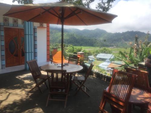 a table with chairs and an umbrella on a patio at Bintang Bungalow Tour & Travel in Kelimutu