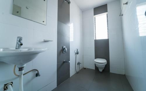 a white bathroom with a sink and a toilet at Hotel Aashish Deluxe Pet Friendly in Kolhapur
