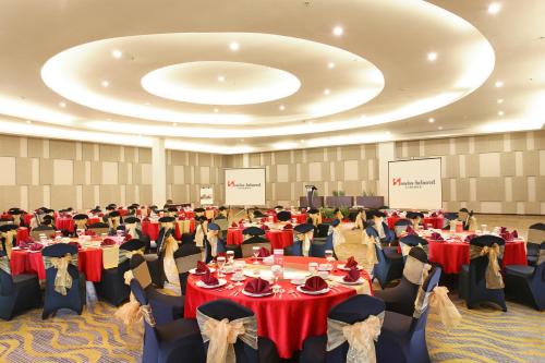 a large banquet hall with tables with red tablecloths at Swiss-Belhotel Cirebon in Cirebon