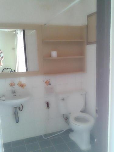 a bathroom with a toilet and a sink and a mirror at M In Korat Service Apartment in Nakhon Ratchasima