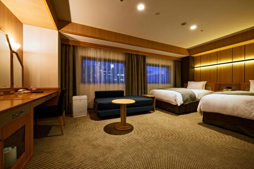 a hotel room with two beds and a desk at Sendai Kokusai Hotel in Sendai