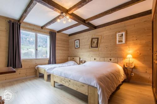 two beds in a room with wooden walls at Auberge Du Fraizier in Thônes