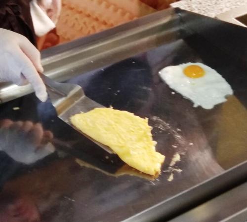 Iemand snijdt een ei op een grill. bij Fenals Garden in Lloret de Mar