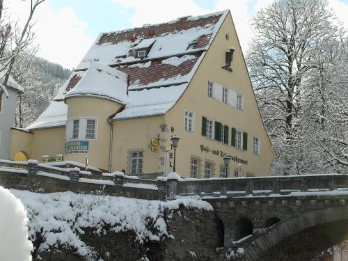 a building with a snow covered roof next to a bridge at Hotel Alpin Murau in Murau