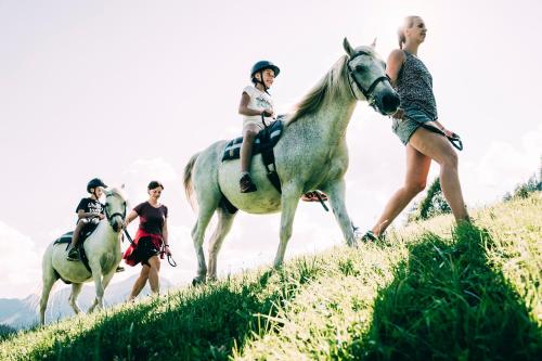 a group of people riding horses on a hill at Kinderhotel Stegerhof in Donnersbachwald