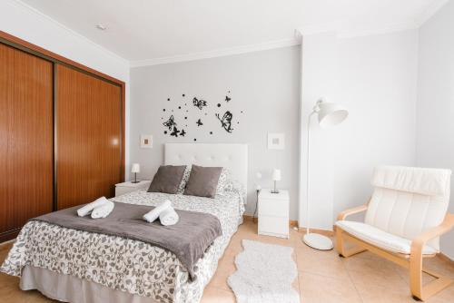 een witte slaapkamer met een bed en een stoel bij Gelvesturist in Gelves