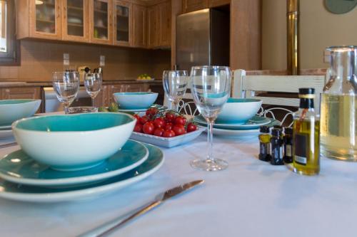 a table with plates and bowls and wine glasses at PaxosBlue Suites & Villas in Gaios