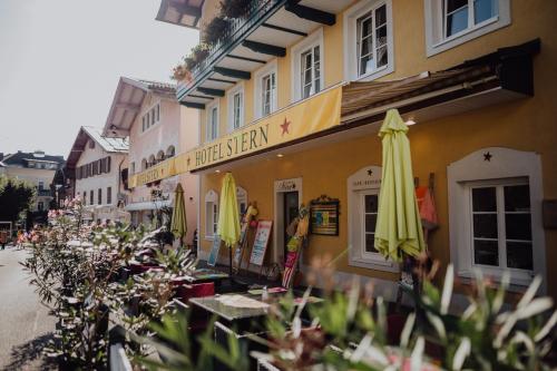 a building with umbrellas and tables outside of it at Das Hotel Stern, B&B KG - digital & contactless check-in in Sankt Gilgen