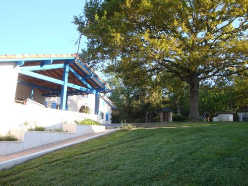 a park with a tree and a building with a tree at Chambre d'Hôtes au Sargaillon in Pouillon
